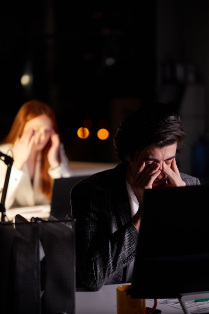 Hombre caucásico joven exhausto soñoliento que trabaja tarde en la