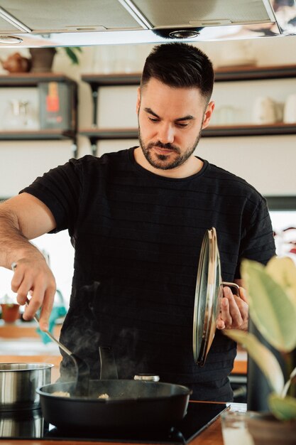 Hombre cocinando en una elegante cocina con una sartén hombre cocinando ...