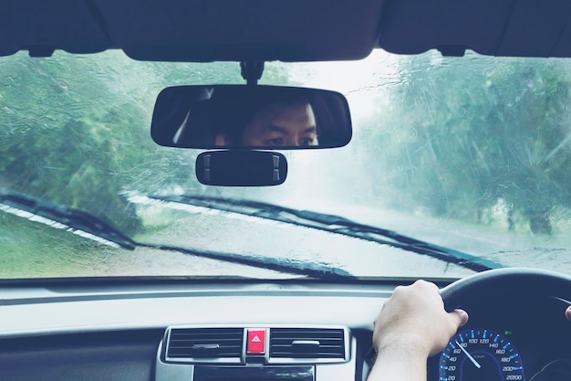 Hombre conduciendo un coche en fuertes lluvias Foto gratis