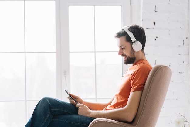 Hombre escuchando música junto a la ventana Foto Gratis