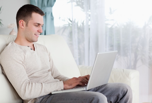 Hombre feliz escribiendo en su computadora portátil | Foto Premium