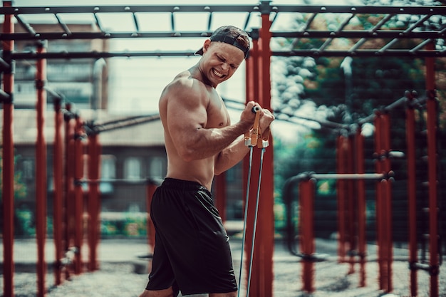 Hombre fitness ejercicio con banda de estiramiento en el gimnasio al aire libre Foto Premium