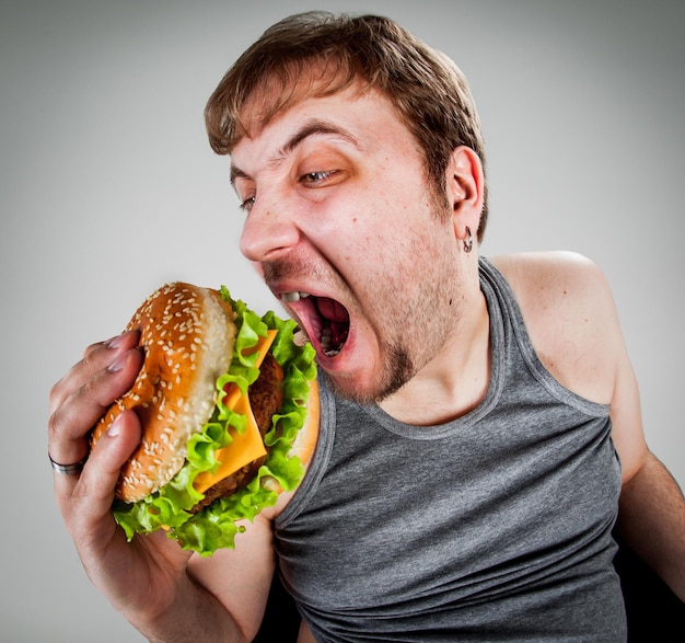 Hombre gordo comiendo hamburguesa sentado en un sillón Foto Premium