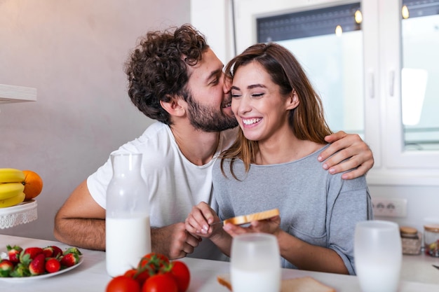 Hombre Joven Cariñoso Besando A Su Esposa Mientras Ella Prepara El Desayuno Hermosa Joven