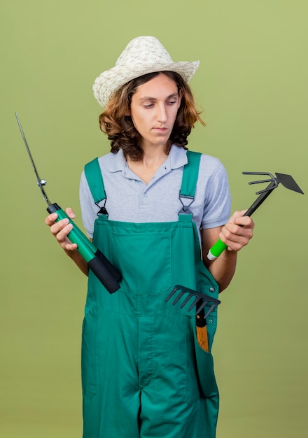 Hombre Joven Jardinero Vestido Con Mono Y Sombrero Sosteniendo Equipos