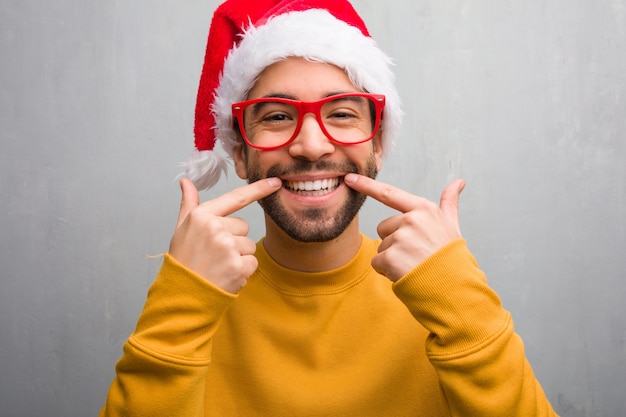 Hombre joven que celebra el día de navidad con regalos sonrisas, apuntando  boca | Foto Premium