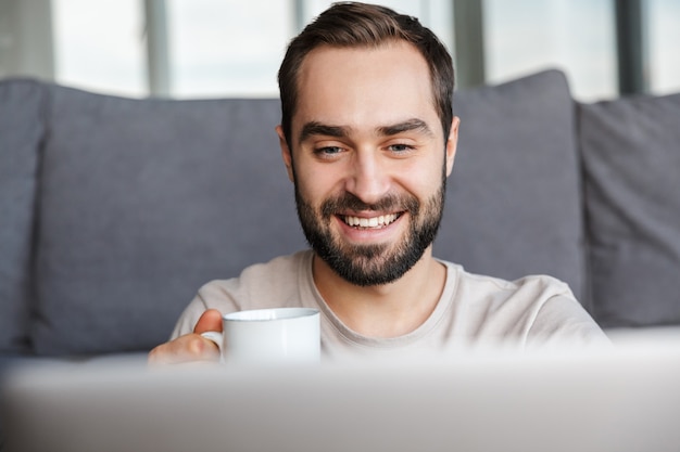 Un Hombre Joven Sonriente Feliz Adentro En Casa Usando La Computadora