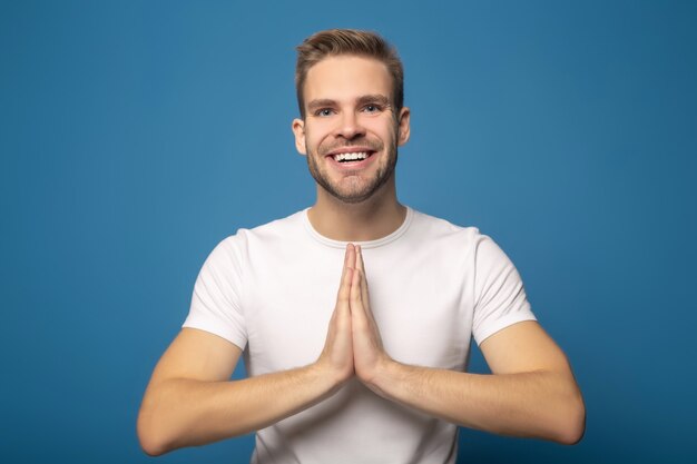 Hombre Joven Sonriente Con Las Manos Rezando Aisladas En Azul Foto Premium