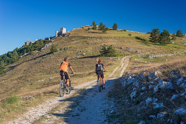 Hombre Y Mujer Montando Mtb A Las Ruinas Del Castillo En La Cima De La