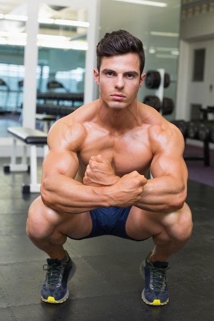 Hombre musculoso sin camisa que dobla los músculos en el