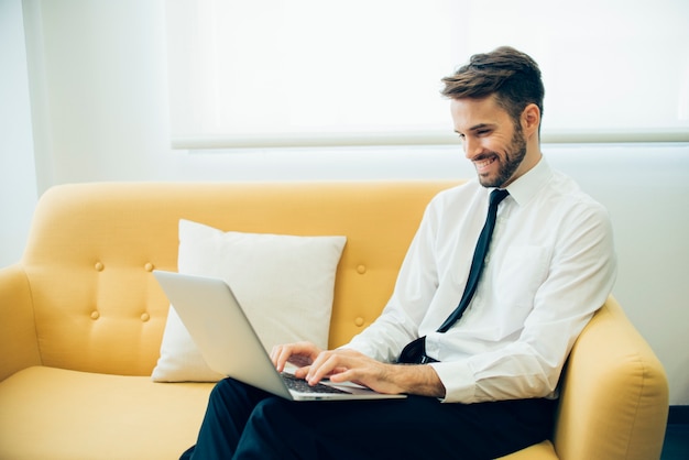 Hombre de negocios guapo riendo y trabajando con su portátil ...