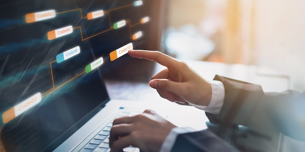 Hombre de negocios que señala la etiqueta de código de icono coherente y la pantalla de desarrollo de aplicaciones en la computadora portátil. Foto Premium