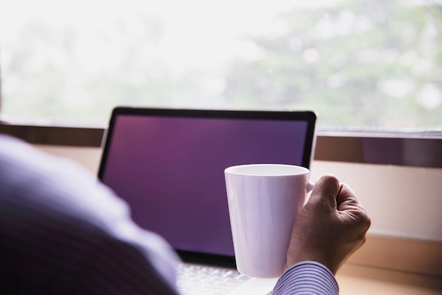 Hombre de negocios trabajando con computadora con taza de café en la habitación del hotel Foto gratis