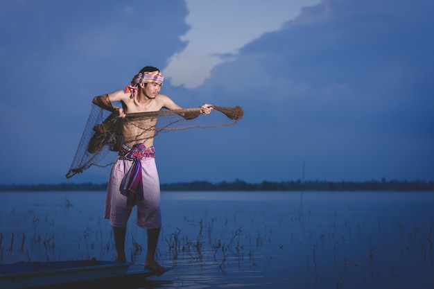 El hombre de la pesca utiliza una red para atrapar peces en el lago al