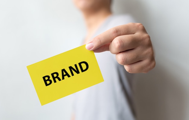 Man holding yellow card and the word brand. branding for success concept Premium Photo