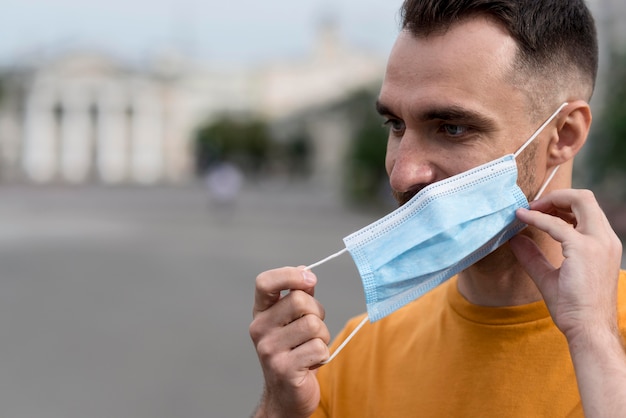 Hombre quitándose la máscara médica al aire libre | Foto Gratis