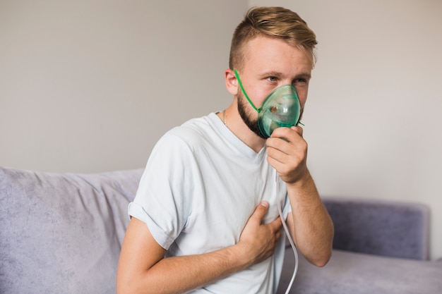 Hombre en sofá con nebulizador de asma Foto gratis