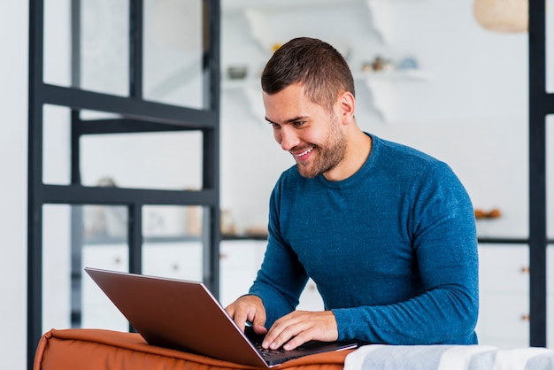 Hombre sonriente trabajando en la computadora portátil desde casa ...