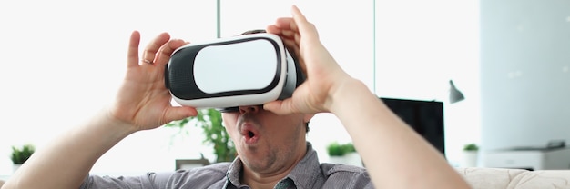 Hombre sorprendido con gafas de realidad virtual sentado en el sofá en