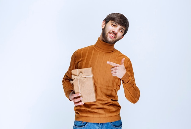 Hombre sujetando una caja de regalo de cartón y presentándola Foto Gratis