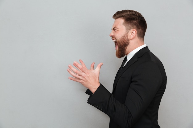 Hombre en traje gritando y gesticulando con las manos Foto gratis