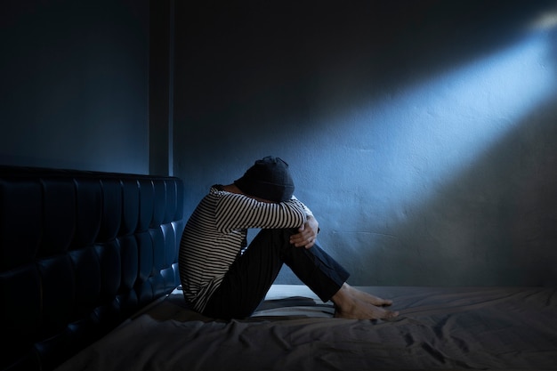 Hombre Triste En La Cama En El Cuarto Oscuro Foto Premium