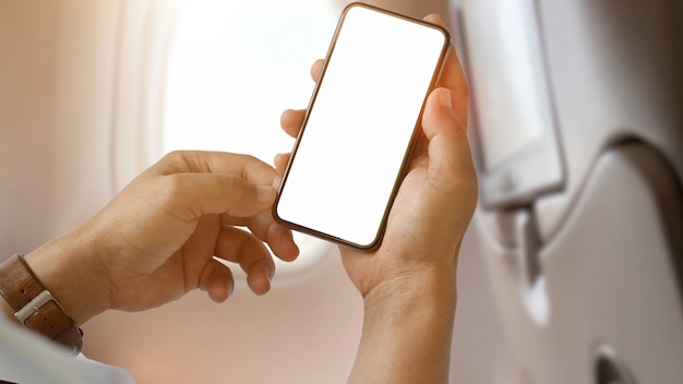 Hombre usando la pantalla en blanco del teléfono inteligente en el avión Foto Premium