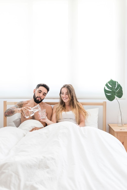 Hombre Vertiendo Agua En Vaso Para Su Esposa En Cama Foto Gratis 6079