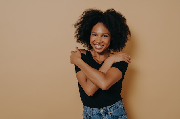 Imagen De Hermosa Joven Complacida De Piel Oscura Con Peinado Afro Voluminoso Abrazándose A Sí