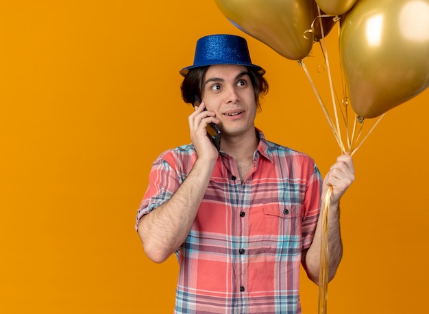 Impresionado apuesto hombre caucásico vestido con gorro de fiesta azul