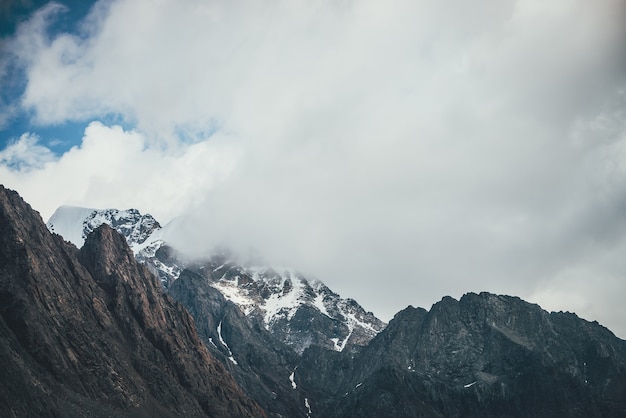 Impresionante paisaje de montaña con montañas nevadas en nubes bajas