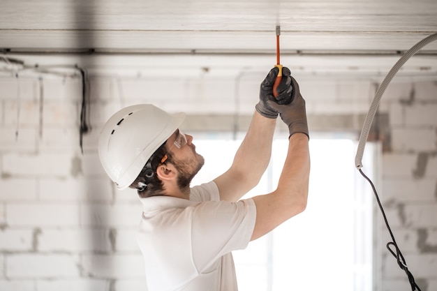 Instalador electricista con una herramienta en sus manos, trabajando