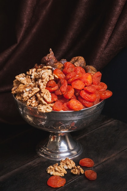 Jarrón con frutos secos y nueces en vajilla metálica del este antiguo