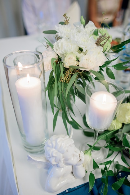 Jarrones de cristal con velas blancas de pie en la mesa de la cena