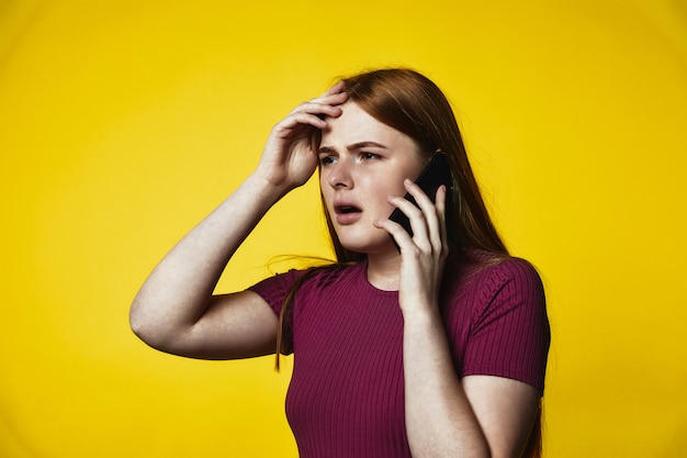 Joven caucásica pelirroja molesta está hablando por el teléfono celular |  Foto Gratis