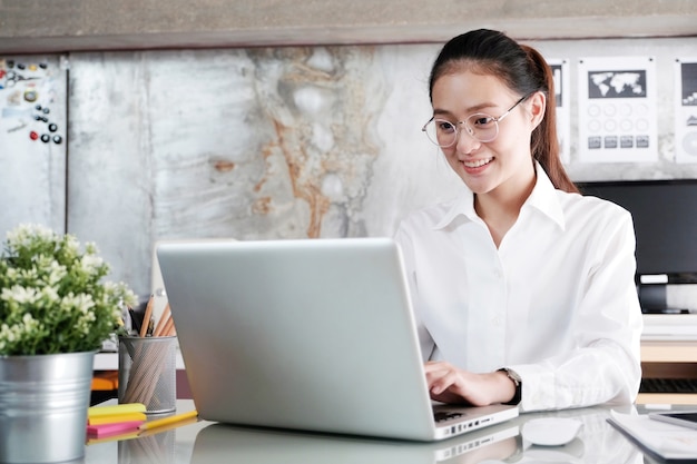 Joven empresaria asiática trabajando con la computadora portátil ...