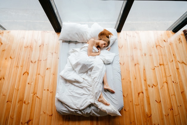 Joven Flaca Hermosa Niña Descalza Acostada En La Cama Blanca Con Una Manta Y Almohadas Y Dormir 