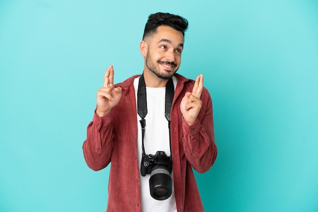 Joven fotógrafo hombre caucásico aislado sobre fondo azul con los dedos