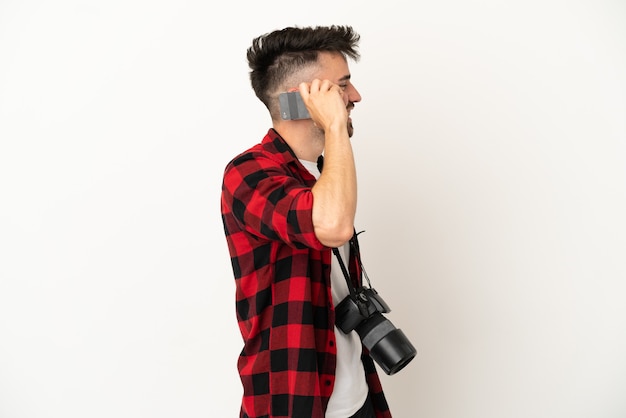 Joven fotógrafo hombre caucásico aislado sobre fondo blanco manteniendo