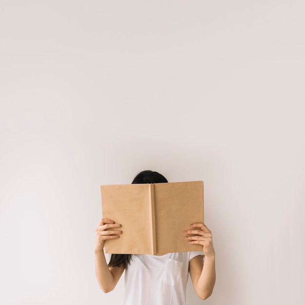 Joven Morena Escondiendo La Cara Detrás Del Libro Foto Gratis