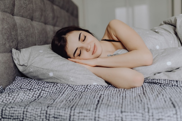 Joven mujer durmiendo. hermosa joven sonriente mujer durmiendo en la cama Foto gratis