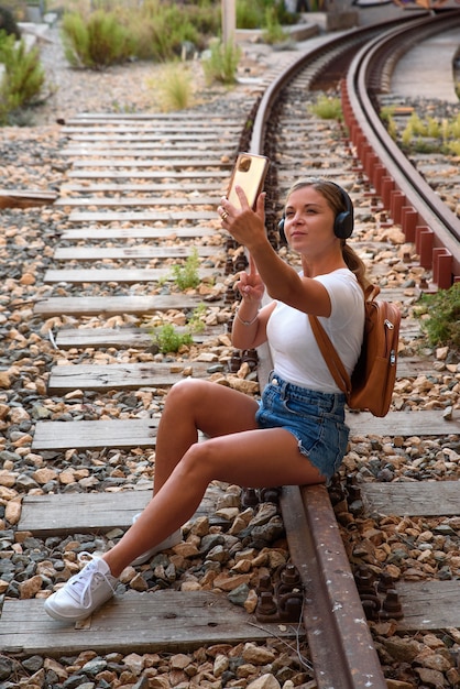 Joven Mujer Rubia En Camiseta Blanca Sentada Sobre Los Rieles Del Tren Toma Fotografías Con Su