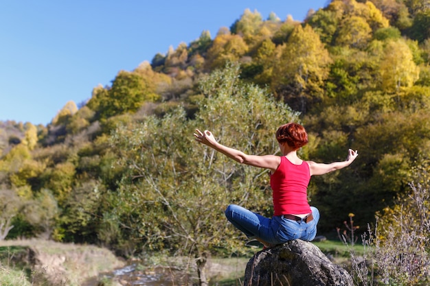 Joven Mujer Sentada Sobre Una Piedra Y Medita Sobre El Fondo De Un Río Bosque Y Cielo Azul En