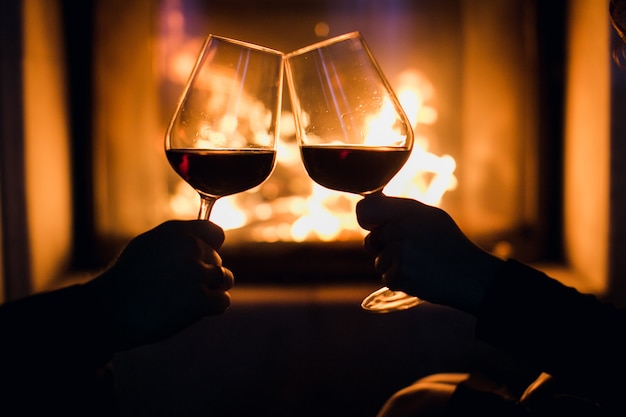 Joven pareja cena romántica con vino sobre fondo de chimenea | Foto Premium