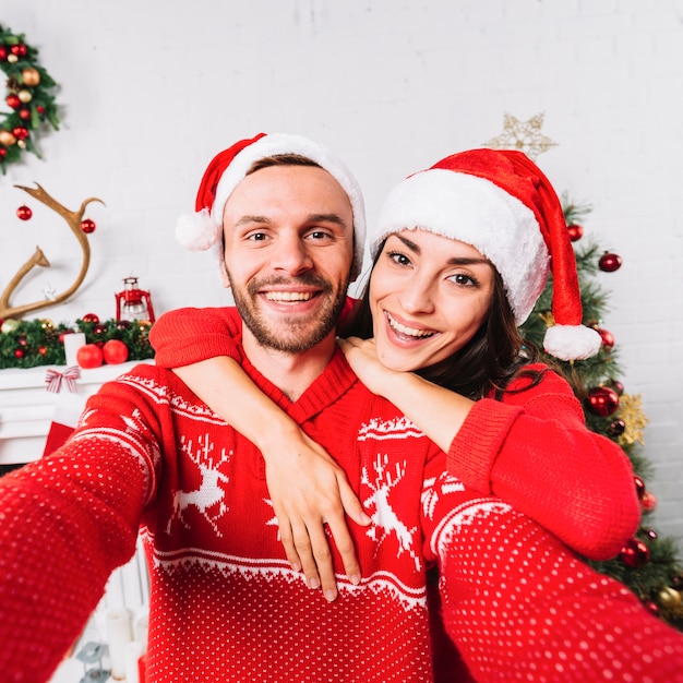 Joven Pareja Feliz Abrazando En Sombreros De La Navidad Foto Gratis