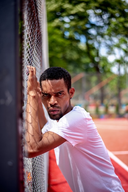 Jugador de baloncesto negro sosteniendo la valla de ...