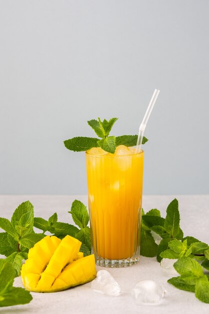 Jugo de mango recién exprimido con hielo en vaso con una pajita mango