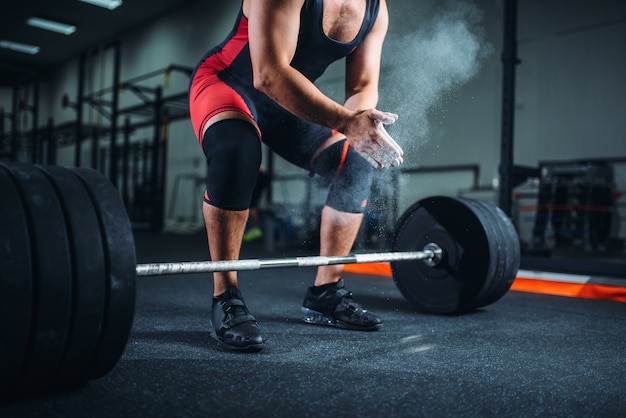 Levantador De Pesas Masculino En Ropa Deportiva Se Frota Las Manos Con Talco Preparacion Para El Ejercicio Con Barra En El Gimnasio Foto Premium