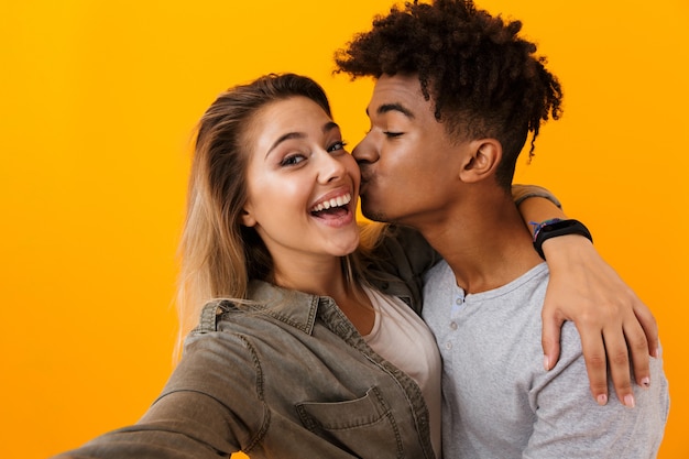 Linda Joven Pareja Amorosa Posando Aislada Sobre Pared Amarilla Abrazándose Tomando Un Selfie 