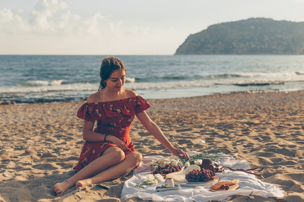 Linda mujer en vestido rojo sentada en la playa durante el día Foto Gratis